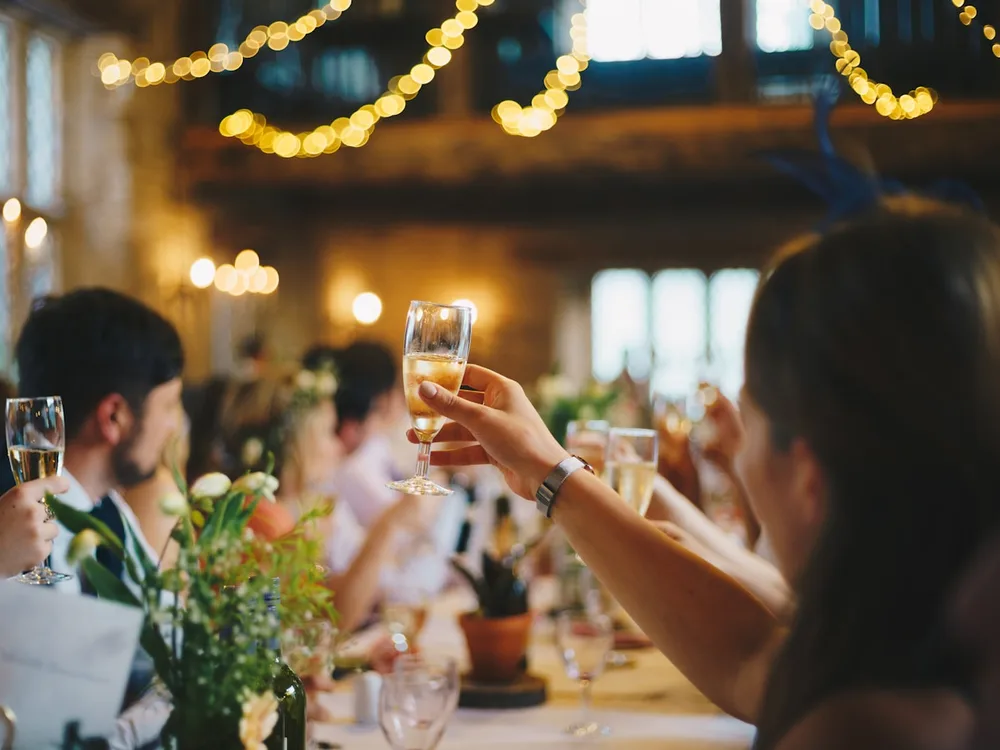 Gäste stoßen mit Sekt in der geschmückten Scheune an